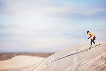 Image showing Sandboard, desert and mockup with a sports man outdoor on the sand dunes for recreation, fun or adventure. Sky, nature and mock up with a male athlete or sandboarding moving downhill at speed