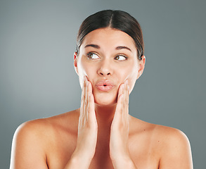 Image showing Face, thinking and botox with a model woman in studio on a gray background for beauty or skincare. Hands, cheeks and idea with an attractive young female touching her skin after collagen treatment