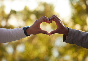 Image showing Hands, heart and love with a couple outdoor on a date, bonding during summer for romance. Nature, emoji or hand sign with a man and woman outside in a park or natural environment on a sunny day