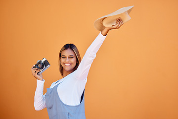 Image showing Happy woman, photographer and retro camera on an orange wall for advertising vacation, holiday or creativity. Person with a smile and hat for summer travel photography, memory and color background