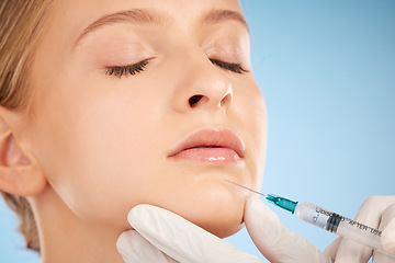 Image showing Woman, studio and botox injection for lip filler, beauty and anti aging skincare process by blue background. Model, facial plastic surgery and syringe needle with doctor, surgeon or cosmetic expert