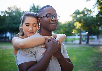 Image showing Love, peace or couple of friends hug in a park bonding on a relaxing romantic date in nature together. Interracial, young black man and happy woman embrace enjoying quality time on a holiday vacation