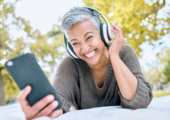 Image showing Headphones, music and old woman with phone at park streaming radio or podcast. Social media, cellphone and happy, elderly and retired female with mobile, laughing at funny meme and enjoying audio.