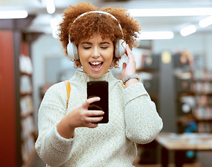 Image showing Headphones, phone and woman in the library with music, radio or podcast for study motivation. Happy, excited and female college student from Brazil listening to song, album or playlist in book store.