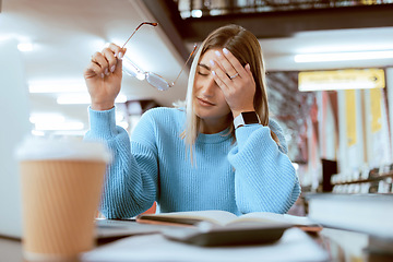 Image showing Woman student, tired with headache and university burnout, stress about paper deadline or study for exam in library. Campus, college studying fatigue with scholarship problem, pain and mental health