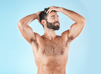 Image showing Shampoo, keratin and haircare with a man model cleaning his hair for hygiene in studio on a blue background. Water, wet and treatment with a handsome muscular male washing his head in the bathroom