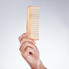 Image showing Hand, comb and haircare with a man barber in studio on a gray background for grooming or hair styling. Salon, bamboo and beauty with a male hairdresser holding a tool to groom or style closeup indoor