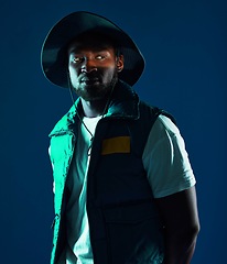 Image showing Fashion, shadow and black man model in a studio with a cool, stylish and casual outfit with lighting. Edgy, style and trendy fashionable African male posing while isolated by a blue background.