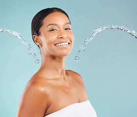 Image showing Black woman, portrait and skincare with water splash, blue background and cleaning cosmetics in studio. Face of female model, body shower and beauty for healthy skincare, happy wellness or aesthetics