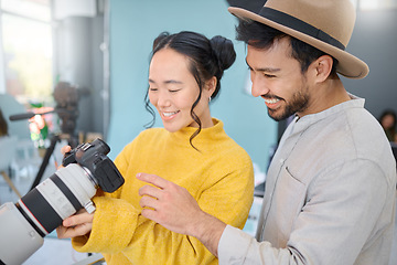 Image showing Creative, photography and photographer talking to a model while looking at pictures on a camera. Discussion, photoshoot and young cameraman choosing a image with a woman in a creative artistic studio