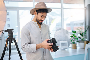 Image showing Photographer, camera and man in studio for catalog, selection and photo, happy and photo shoot. Backstage, photography and professional asian male choosing picture for fashion, magazine and creative