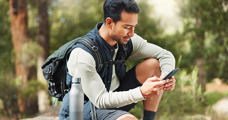 Image showing Nature hiking man, typing phone and sitting on rock for rest, break or relax with backpack outdoor. Forest adventure, woods explorer and smartphone for coordinate direction on gps navigation by trees