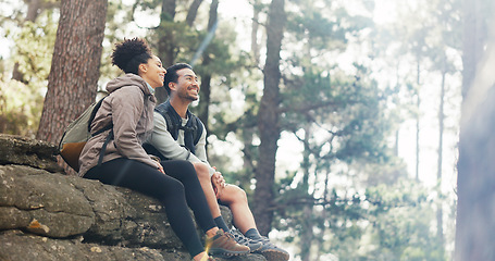 Image showing Nature, hiking and a couple relax on adventure trail in forest and sitting on a rock. Health, happy man and woman pointing at natural landscape while relaxing in woods with trees, fitness and freedom