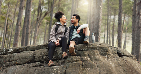 Image showing Nature, hiking and a couple relax on adventure trail in forest and sitting on a rock. Health, happy man and woman pointing at natural landscape while relaxing in woods with trees, fitness and freedom