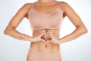 Image showing Fitness, heart shape and woman body in a studio for self love, motivation and positivity. Diet, health and slim female model with a love hand sign for weightloss and wellness by a gray background.