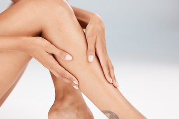 Image showing Legs, skin care and body of a woman in studio for hair removal, epilation or waxing for smooth shine. Natural model person hands for spa beauty treatment, health and wellness on a grey background