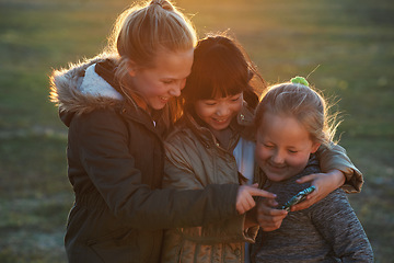 Image showing Friends, girls outdoor and smartphone for connection, online games and happiness on summer break. Young people, female children and kids with cellphone, bonding and watching funny videos on field