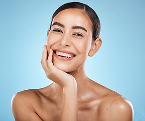 Image showing Portrait, beauty and smile with a model woman in studio on a blue background for natural skincare. Face, skin and cosmetics with an attractive young female posing to promote a luxury product