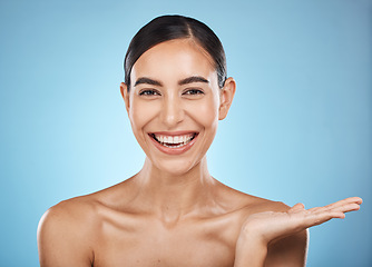 Image showing Face, beauty skincare and woman with product placement in studio isolated on a blue background. Makeup portrait, cosmetics and female model with marketing, advertising or branding space for mockup.