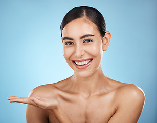 Image showing Portrait, beauty skincare and woman with product placement in studio isolated on a blue background. Face makeup, cosmetics and female model with marketing, advertising or branding space for mockup.