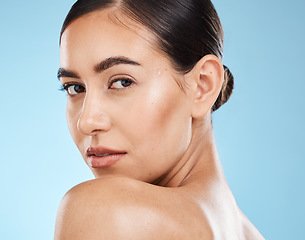 Image showing Portrait, beauty and shoulder with a model woman in studio on a blue background for natural skincare. Face, skin and cosmetics with an attractive young female posing to promote a luxury product