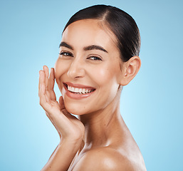 Image showing Portrait, smile and skincare with a model woman in studio on a blue background for natural beauty. Face, skin and cosmetics with an attractive young female posing to promote a luxury product