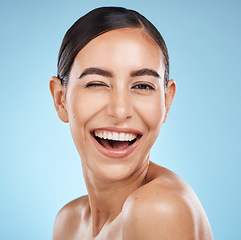 Image showing Face, wink and beauty skincare of woman in studio isolated on blue background. Portrait, makeup and cosmetics of happy female model with healthy, glowing and flawless skin after spa facial treatment.