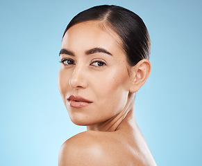 Image showing Portrait, shoulder and skincare with a model woman in studio on a blue background for natural beauty. Face, skin and cosmetics with an attractive young female posing to promote a luxury product