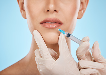 Image showing Closeup, woman and needle on lips for cosmetics, dermatology and treatment for beauty, wellness and against blue studio background. Female, lady and injection for mouth, plastic surgery and skincare