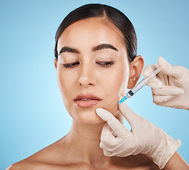 Image showing Needle, woman and plastic surgery for skincare, collagen or beauty clinic in studio. Botox cosmetics, face injection and aesthetic filler for body transformation, change and makeup on blue background