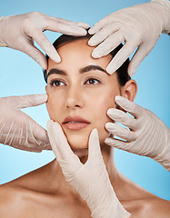 Image showing Plastic surgery, check and hands on the face of a woman isolated on a blue background in a studio. Feeling, skincare and doctors touching a model for a botox, cosmetics or dermatology consultation