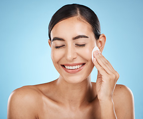 Image showing Skincare, cotton pad and woman in a studio with a cosmetic, natural and facial treatment. Self care, beauty and happy female model with a healthy face or skin routine isolated by a blue background.