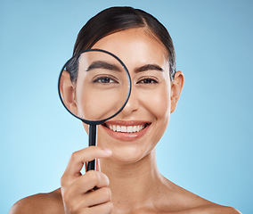 Image showing Magnifying glass, face portrait and skincare of woman in studio isolated on a blue background. Beauty search, makeup and cosmetics of female model with magnifier lens to check aesthetic wellness.