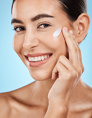 Image showing Portrait, cream and skincare with a model woman in studio on a blue background for natural skincare. Face, skin and lotion with an attractive young female posing to promote a luxury cosmetic product