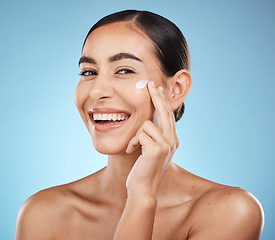 Image showing Portrait, beauty and cream with a model woman in studio on a blue background for natural skincare. Face, lotion and cosmetics with an attractive young female posing to promote a skin product