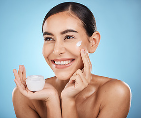 Image showing Face, cream and skincare product of woman in studio isolated on a blue background. Cosmetics, aesthetics and happy female model thinking about lotion, creme or moisturizer for beauty and wellness.