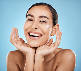Image showing Portrait, hands and cream with a model woman in studio on a blue background for beauty or skincare. Face, skin and lotion with an attractive young female posing to promote a luxury cosmetic product