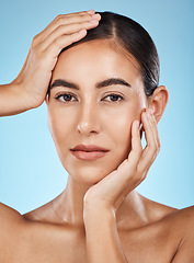 Image showing Portrait, beauty and hands with a model woman in studio on a blue background for natural skincare. Face, skin and cosmetics with an attractive young female posing to promote a luxury product