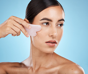 Image showing Skin care, face massage and beauty woman with gua sha for dermatology, cosmetics and wellness. Aesthetic model person with facial scraping stone spa product to relax and glow on blue background