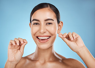 Image showing Woman, flossing in portrait and smile, dental healthcare for fresh breath and clean teeth isolated on blue background. Face, hands and flossing with oral hygiene product and healthy gums in studio