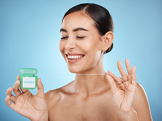 Image showing Woman, floss and smile, face with dental healthcare, fresh breath and teeth cleaning isolated on blue background. Happy flossing, oral hygiene product and mouth health with healthy gums in studio
