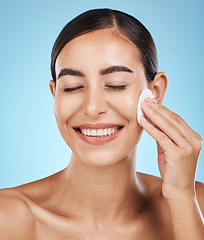 Image showing Beauty, cotton pad and woman in a studio removing makeup, cosmetic or face glamour. Self care, skincare and happy female model with a healthy facial or skin routine isolated by a blue background.