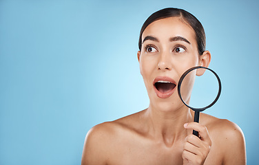 Image showing Woman, face and surprise with magnifying glass, beauty and acne with skin problem isolated on blue background. Skincare cosmetics, wow and facial inspection, mockup space and dermatology in studio