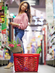 Image showing Grocery basket, store and floor with shopping, black woman or flowers on sale, discount or valentines promotion. Young female person, low angle and search shelf for product, groceries or food in shop