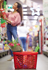 Image showing Shop floor aisle, grocery basket with flowers, black woman or box for choice, sale or discount in valentines promotion. Young african female, low angle and groceries shelf for product deal in store