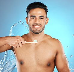 Image showing Portrait, water and man with toothbrush, toothpaste and dental hygiene on blue studio background. Male, gentleman and oral health for clean mouth, smile and fresh breath with healthy gums on backdrop