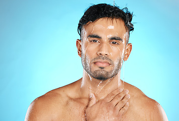 Image showing Skincare, portrait and man in studio for water splash, wellness and grooming on blue background. Face, cleaning and guy model in luxury shower, facial and beauty, skin and routine while isolated