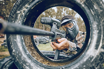 Image showing Gun aim at target with tire, paintball and man outdoor, action on battlefield and soldier focus during war game. Extreme sport, weapon and military mission, exercise and fitness with determination