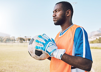 Image showing Black man, football and goalkeeper training on field for focus, exercise or gloves for safety in sunshine. Athlete, soccer goalie and hands with ball, vision or mindset for workout, strategy or sport