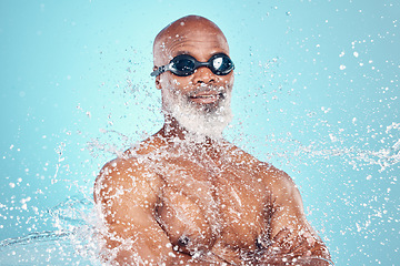 Image showing Water, face and black man with goggles on blue background for wellness, skincare and cleaning. Facial treatment, shower and senior male isolated with splash for hydration, moisturizing and hygiene